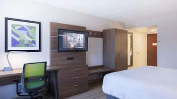 A hotel room with a bed, a desk with a chair, a television, and a wardrobe.