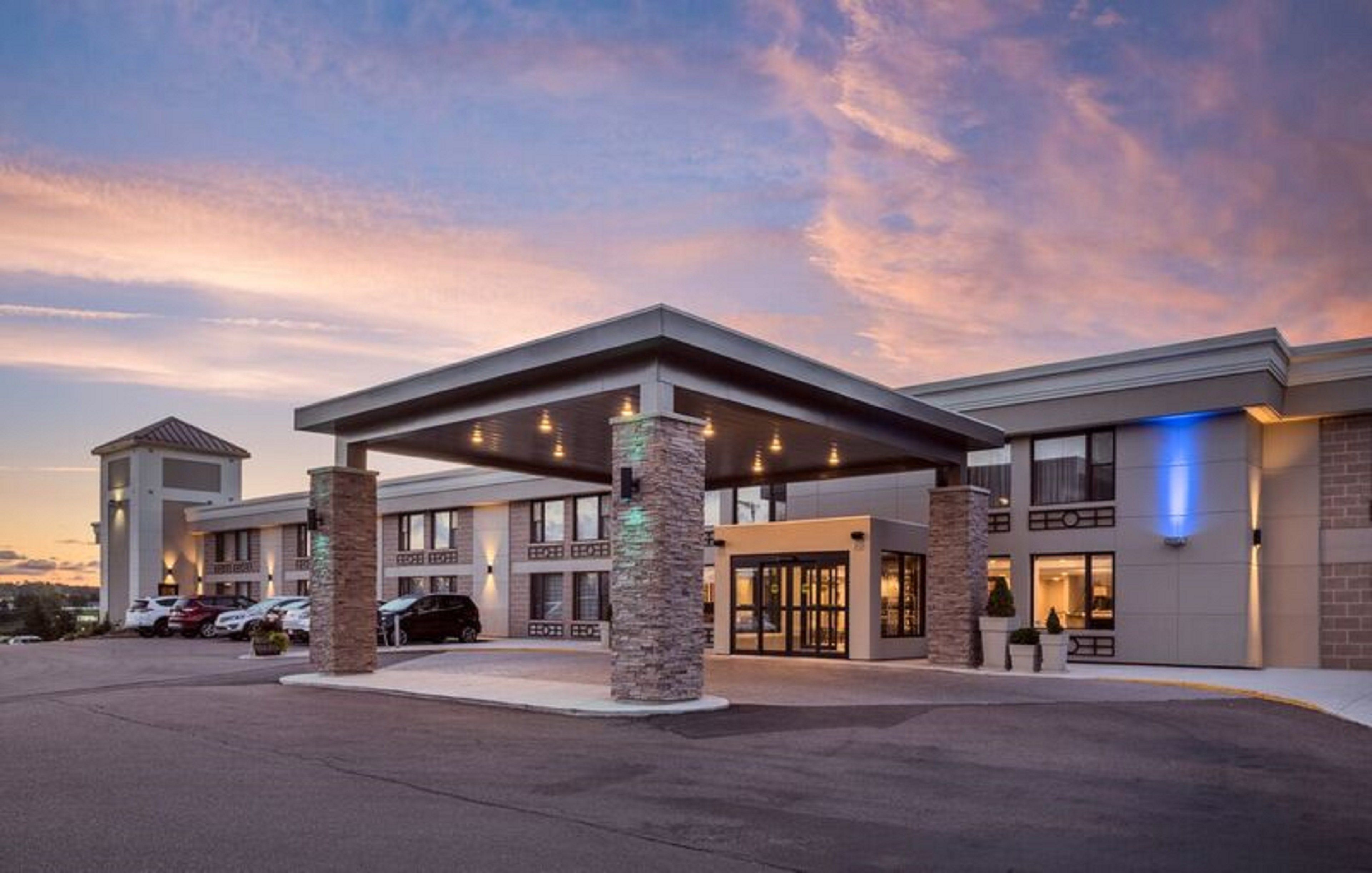 A hotel with a covered entrance, multiple floors, and a parking lot.
