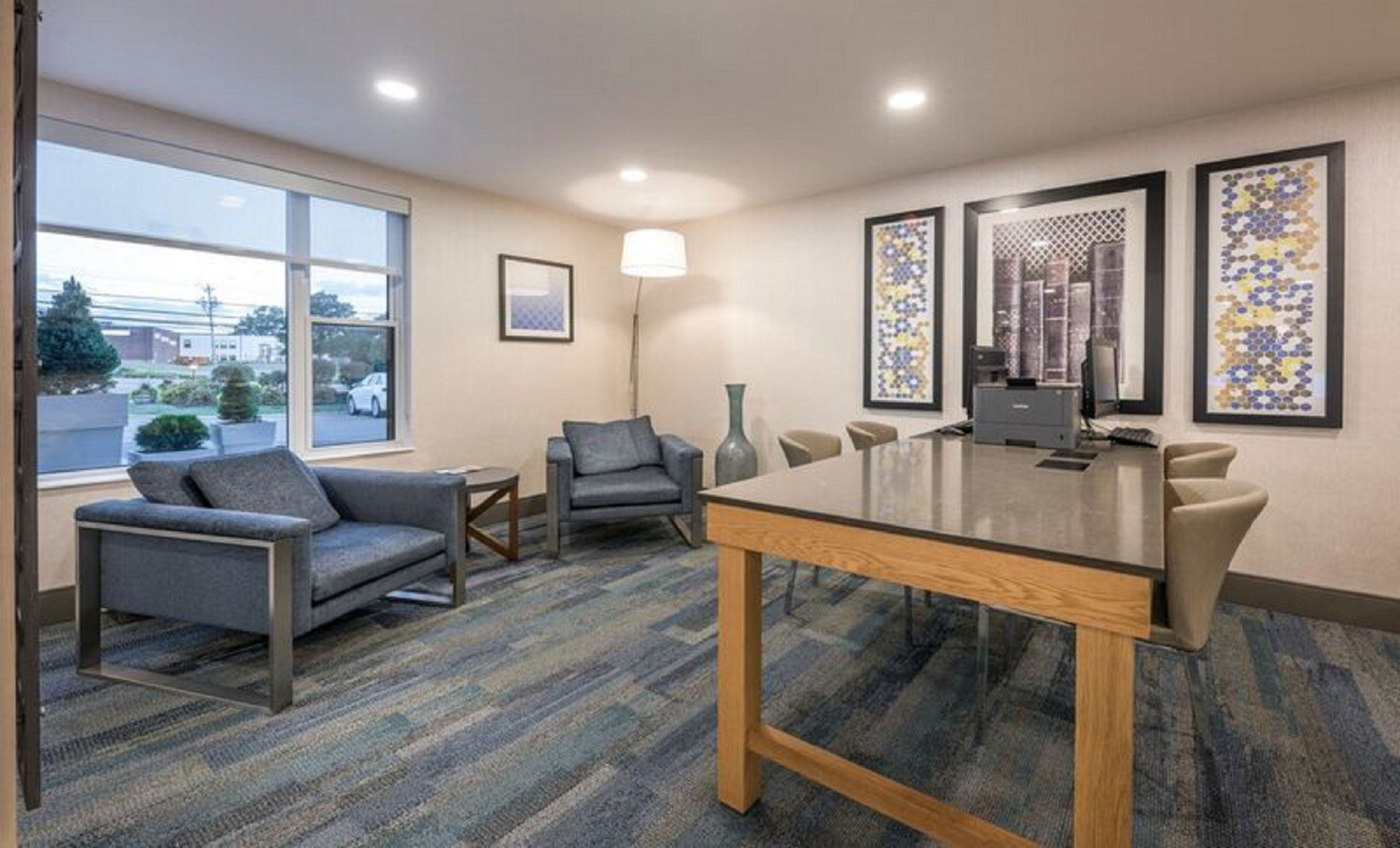 A conference room with a glass table, two sofas, a lamp, and framed artwork on the walls.