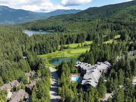 Un resort con campo de golf, piscina y entorno boscoso.