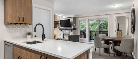 A modern kitchen with a central island, wooden cabinets, and a built-in TV.