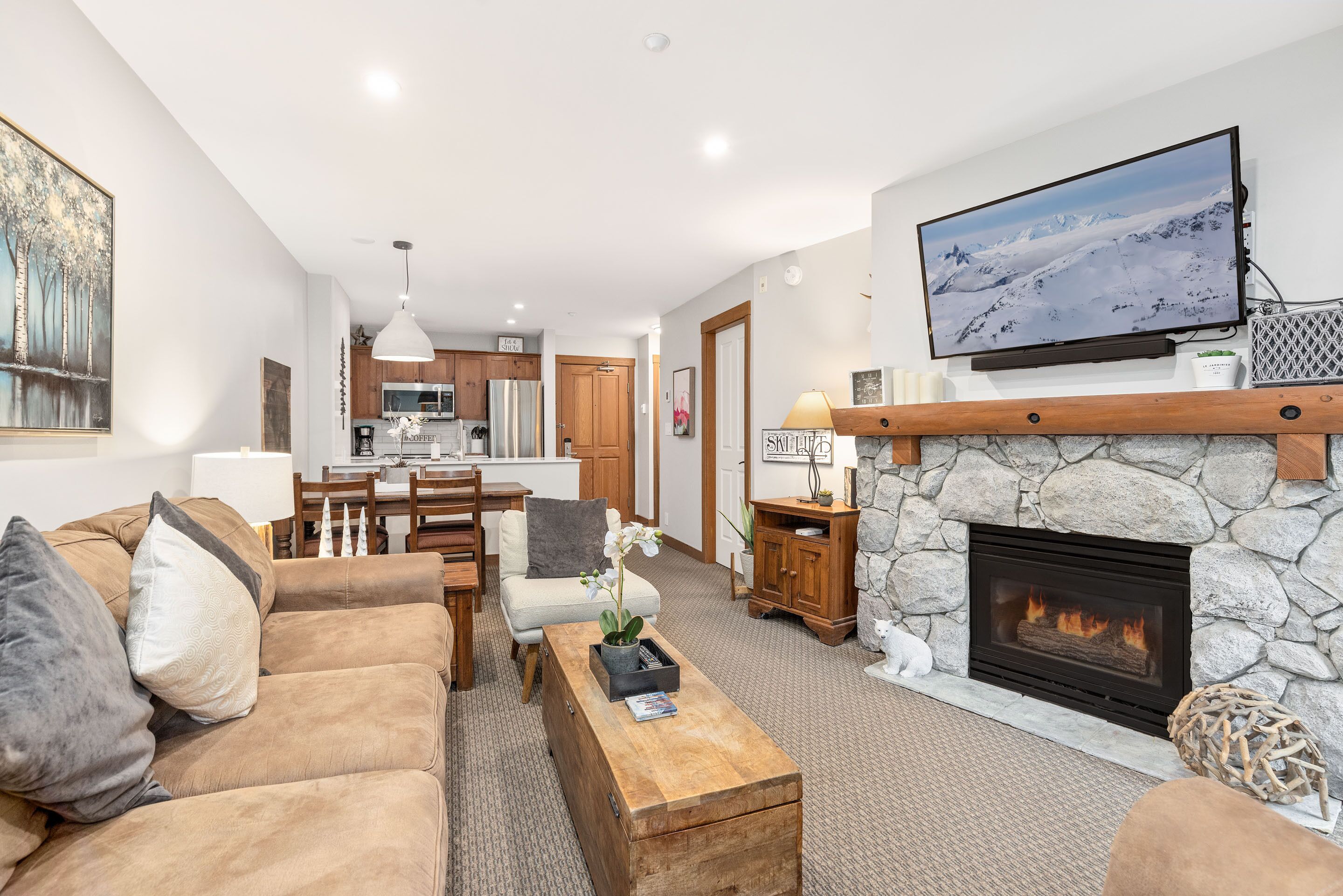 A living room with a stone fireplace, a television mounted above it, and a cozy seating area with a coffee table.
