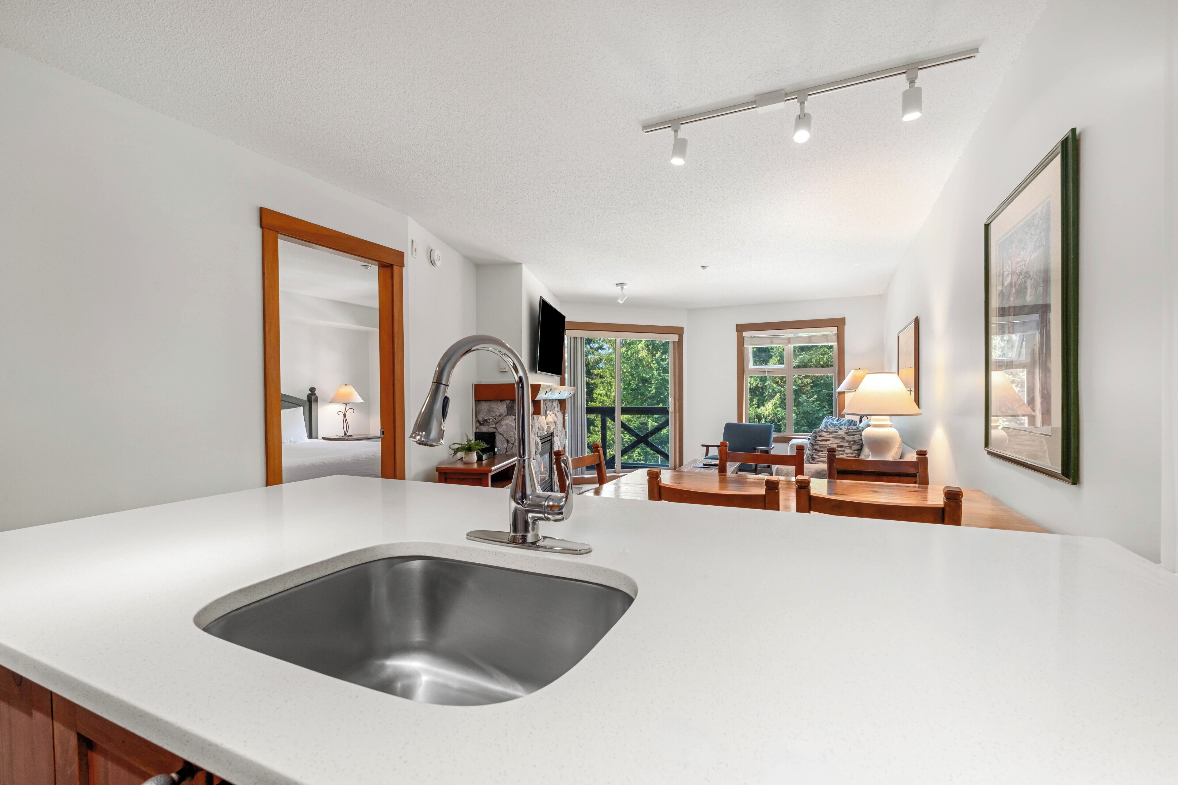 Une cuisine moderne dotée d’un évier en acier inoxydable, de meubles en bois et d’un coin repas avec une table et des chaises.
