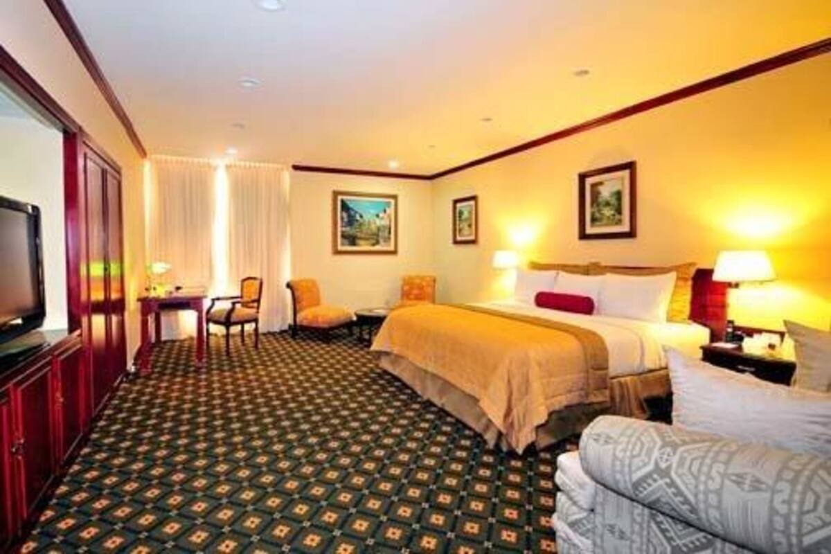 Een hotelkamer met een bed, twee stoelen, een televisie en een bureau.