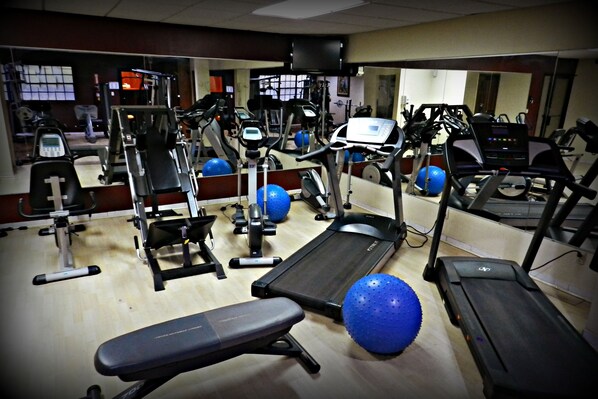 A gym with treadmills, elliptical machines, and free weights.