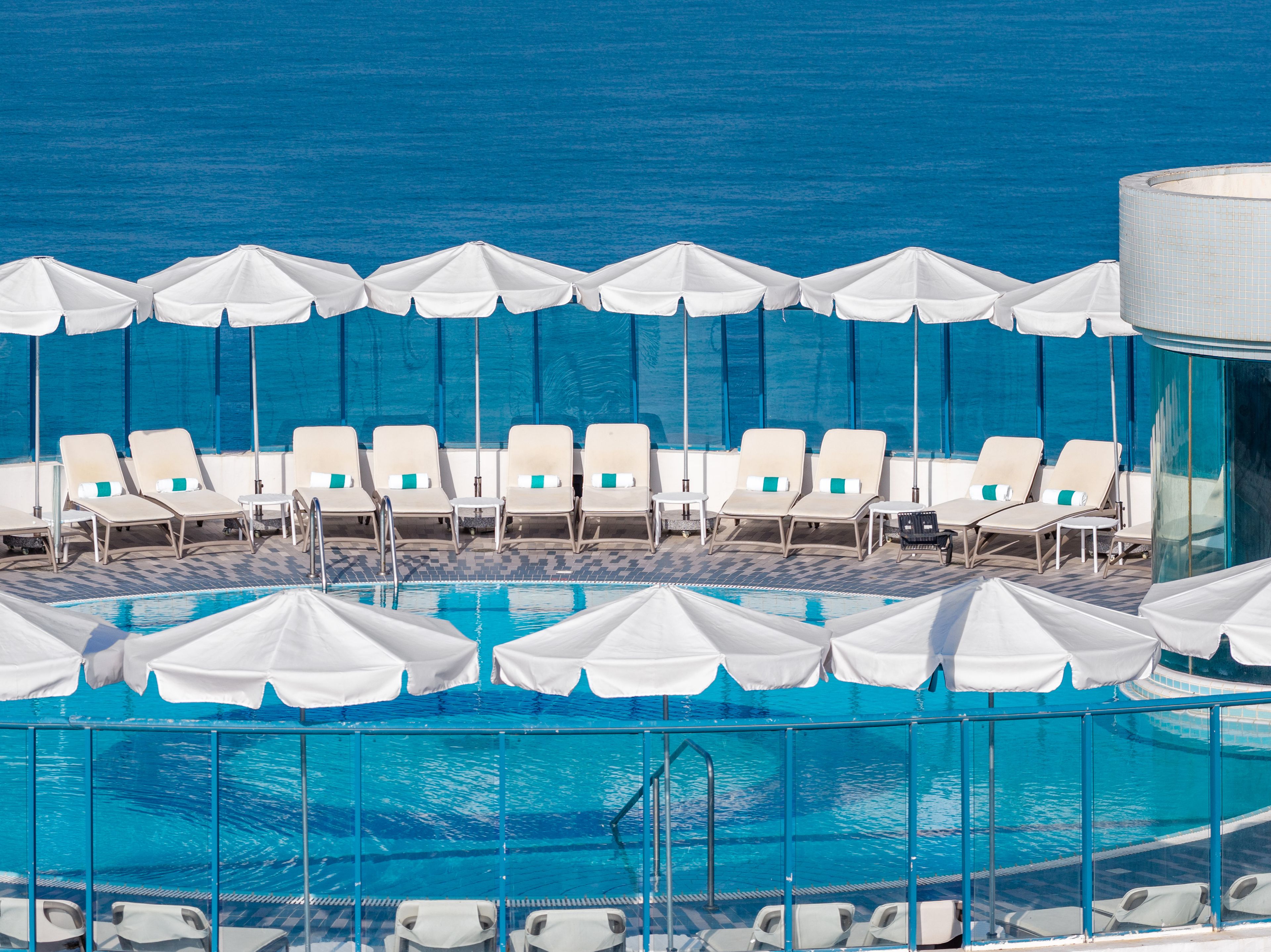 A pool area with white umbrellas and lounge chairs.