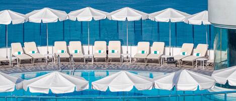 A pool area with white umbrellas and lounge chairs.