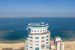 A multi-story hotel with a pool on the upper level, overlooking a beach and the sea. - Sea Tower by Isrotel Design (Tel Aviv)