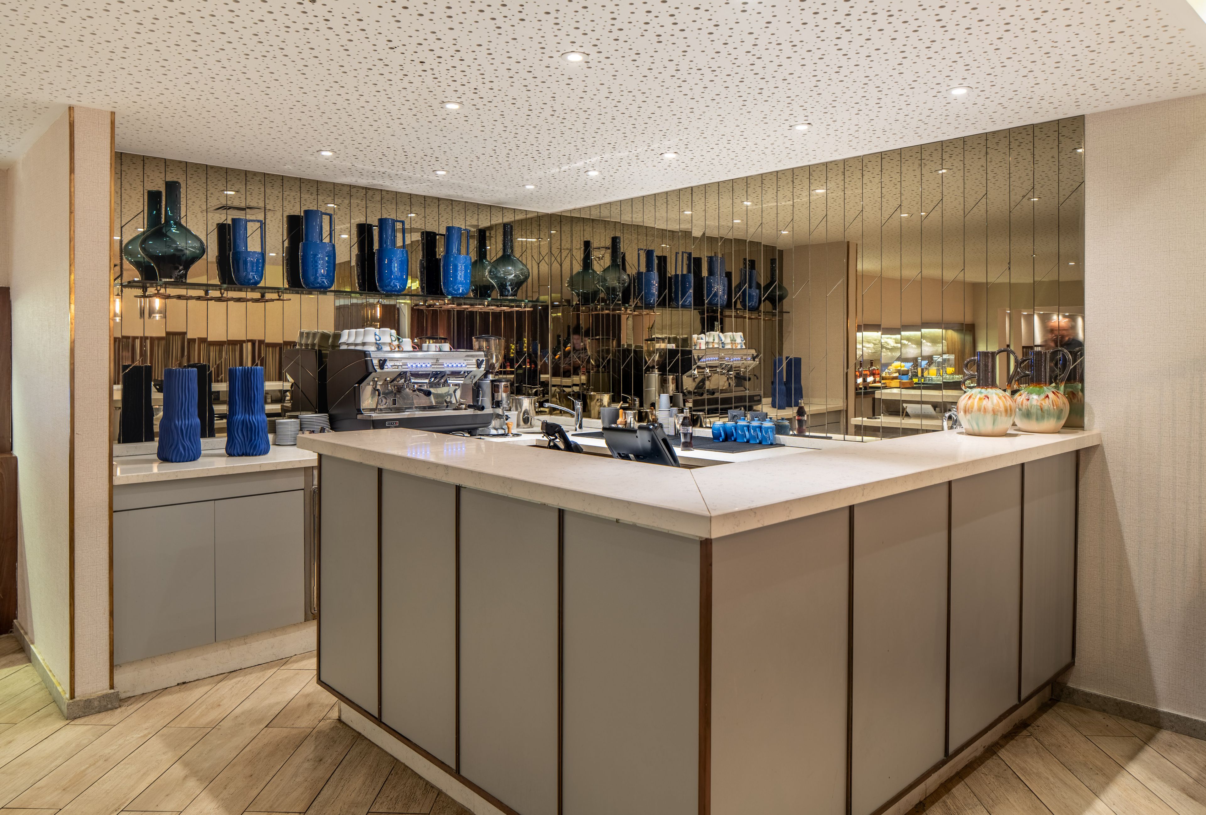 A modern bar area with a central counter, various bar tools, and blue glassware.