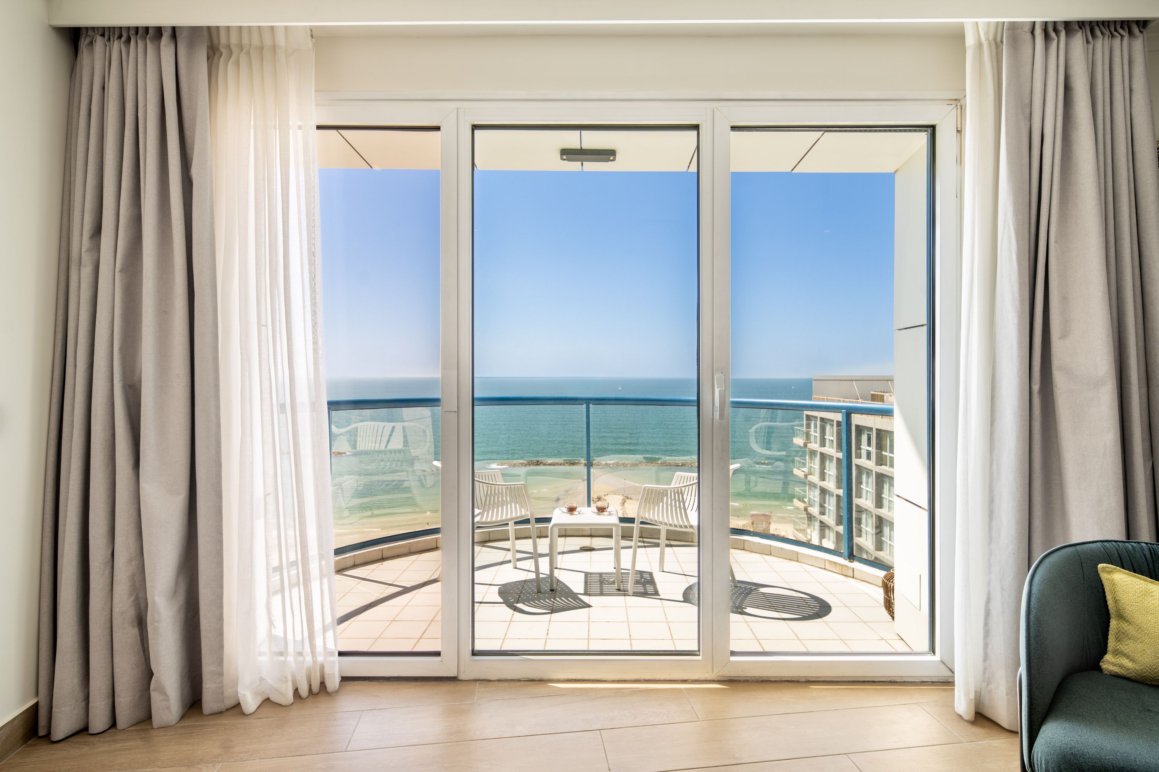 Ein Balkon mit Blick auf das Meer und ein Gebäude gegenüber.
