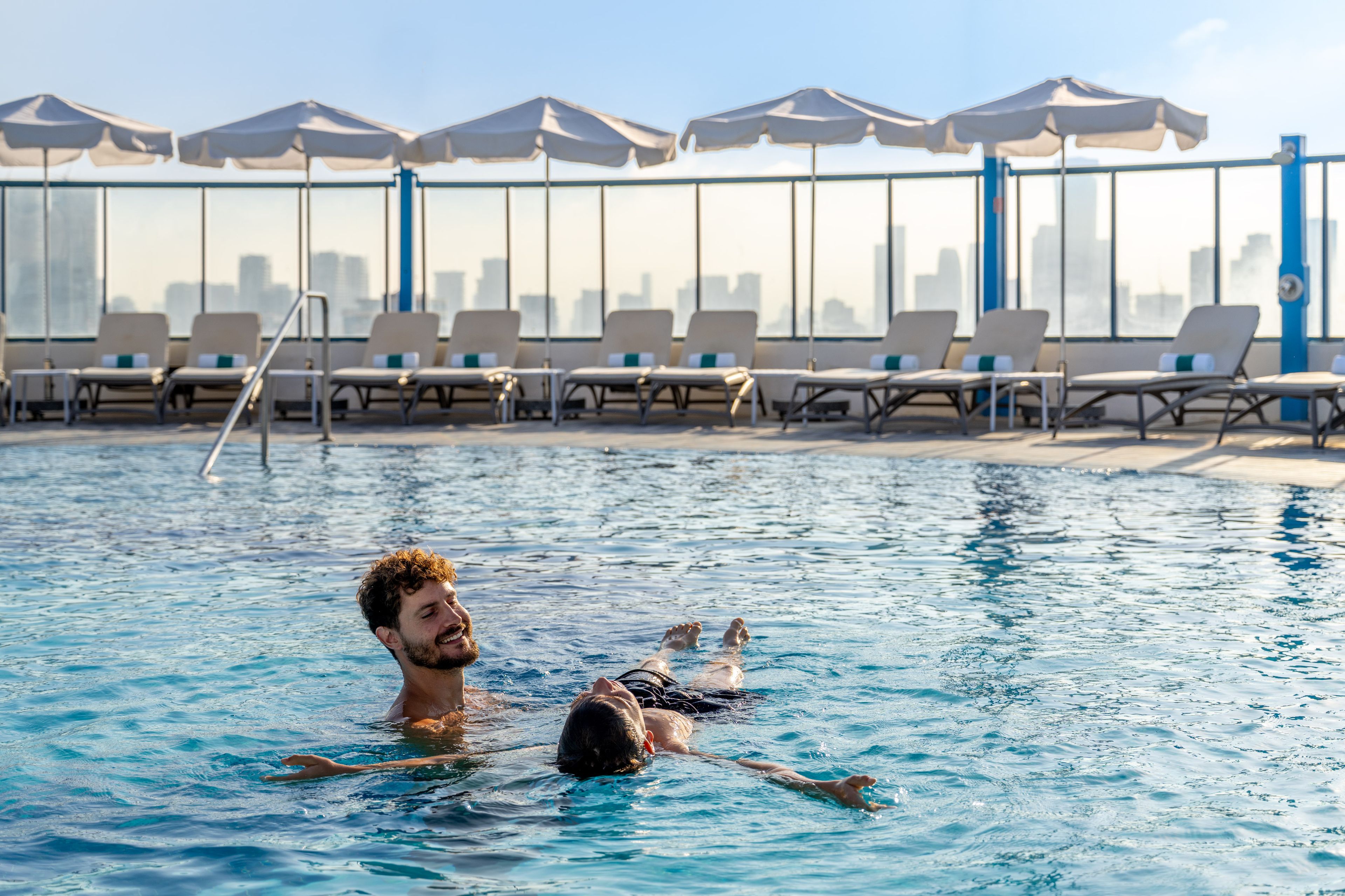 A swimming pool with lounge chairs and umbrellas in the background.