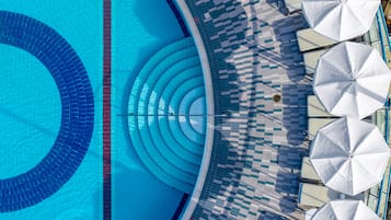 Una piscina con borde y solárium alicatados, con sombrillas.