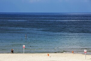 A beach with a clear view of the ocean, a lifeguard tower, and a no swimming sign.