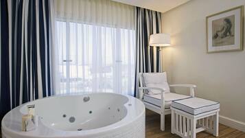 A bathroom with a large bathtub, a white chair, and a small stool.