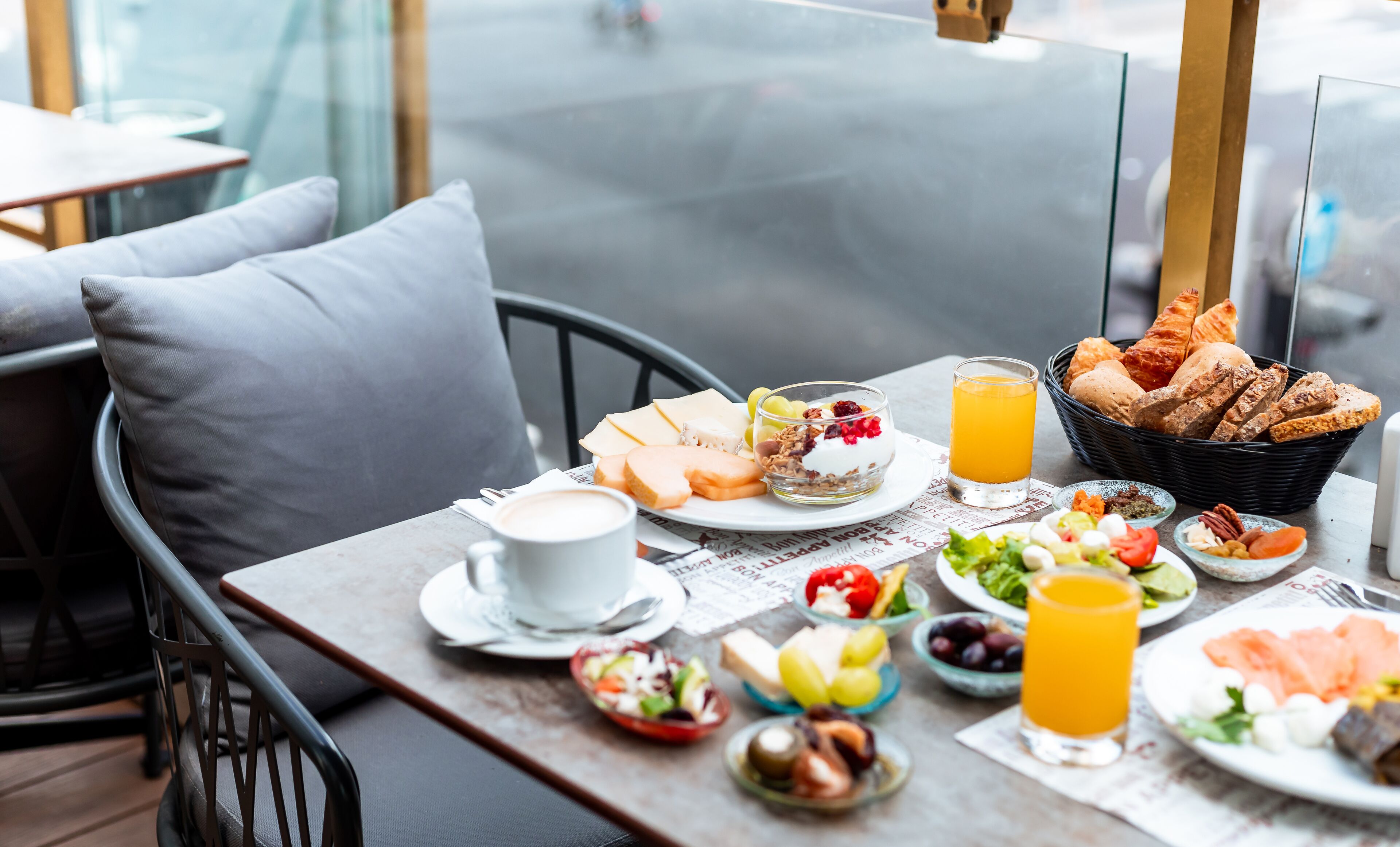 A breakfast table with various food items, a glass of orange juice, and a newspaper.