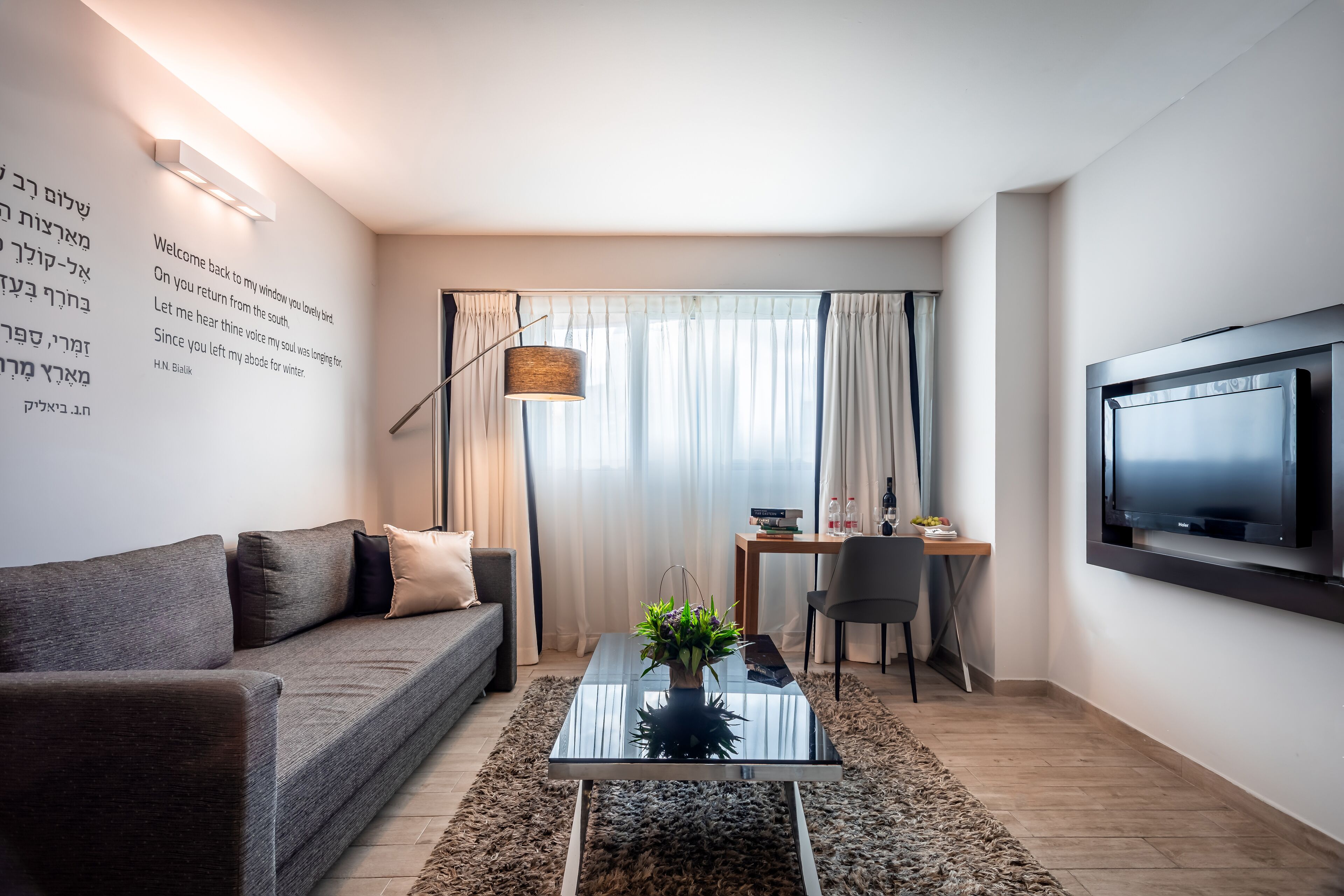A modern living room with a sofa, coffee table, and a TV mounted on the wall.