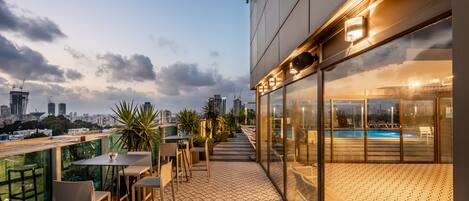 A rooftop terrace with outdoor seating, a pool, and a city view.