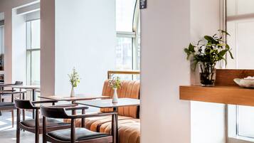 A modern cafe interior with leather seating, a small white vase with flowers, and a plant on a wooden shelf.