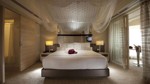Une chambre spacieuse avec un grand lit, deux tables de chevet avec des lampes, une télévision et un plafond décoratif.