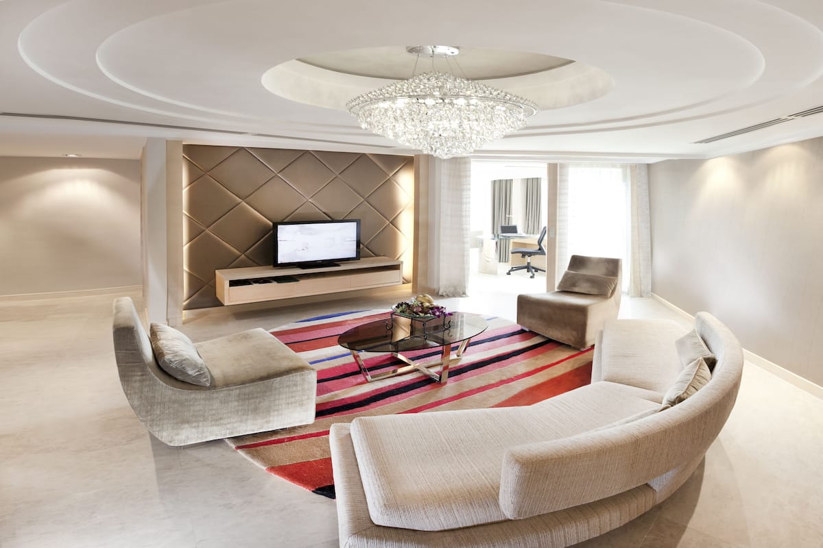 A modern living room with a large TV, a chandelier, and a striped rug.