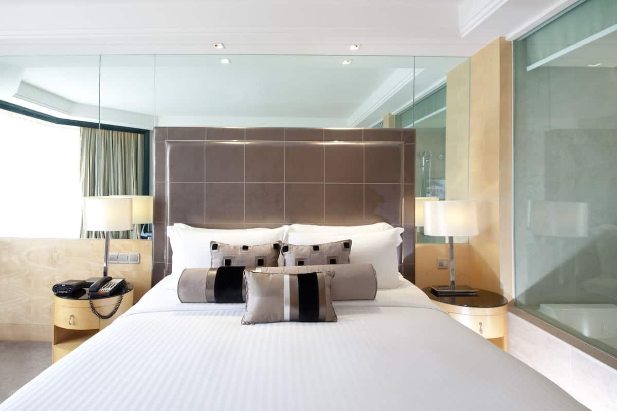 A modern hotel room with a large bed, a bedside telephone, and a nightstand.
