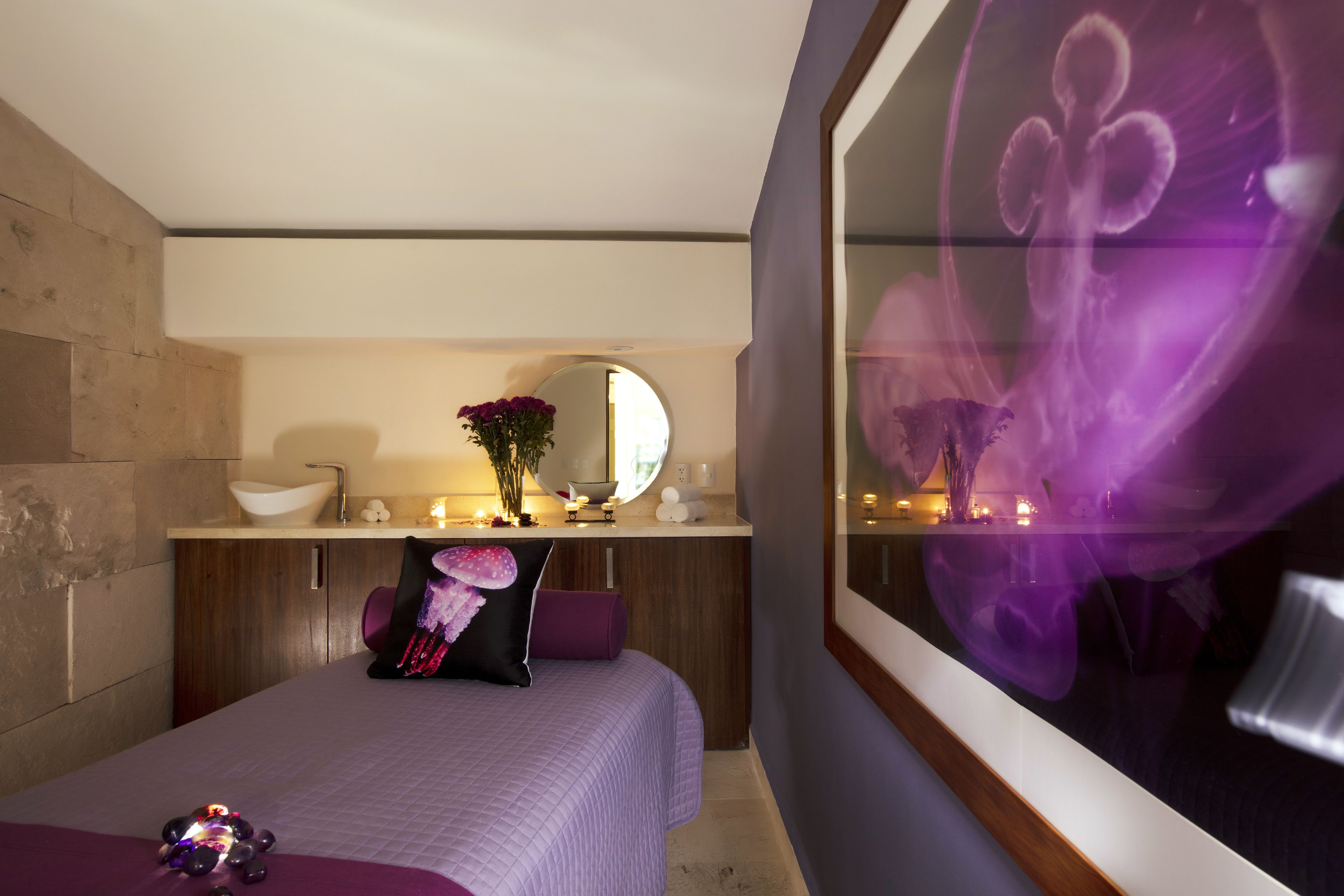 A modern bedroom with a bed, a vanity with a mirror, and a bathroom with a sink and a large mirror.