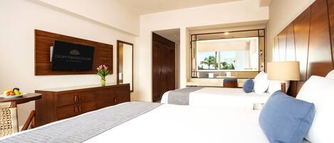 A hotel room with a large bed, a desk with a computer, a mirror, and a television on the wall.