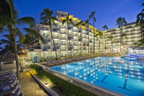 Un hotel con una piscina grande, varios balcones y palmeras.