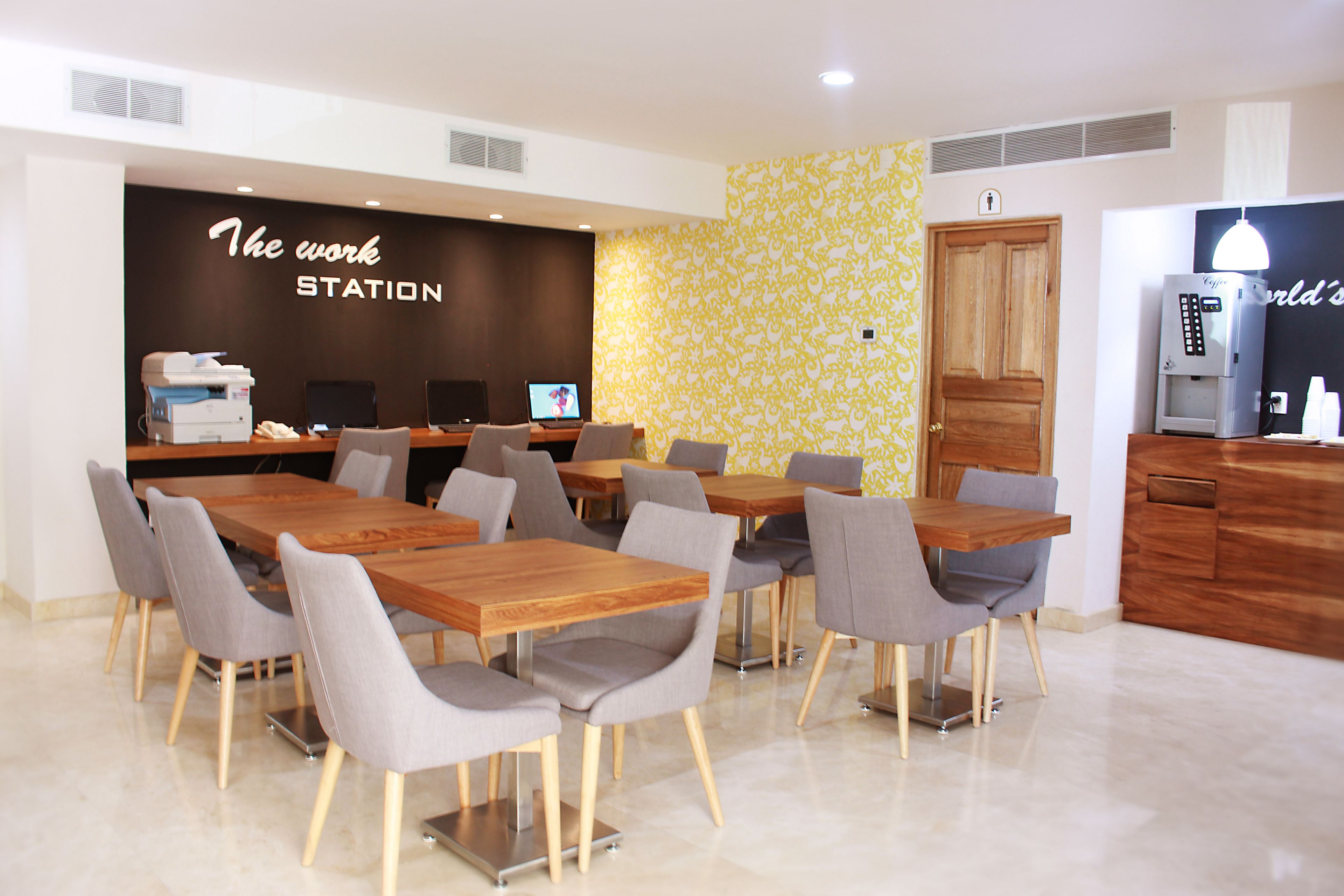 Un espacio de oficina moderno con múltiples puestos de trabajo, una máquina de café y una zona de recepción.