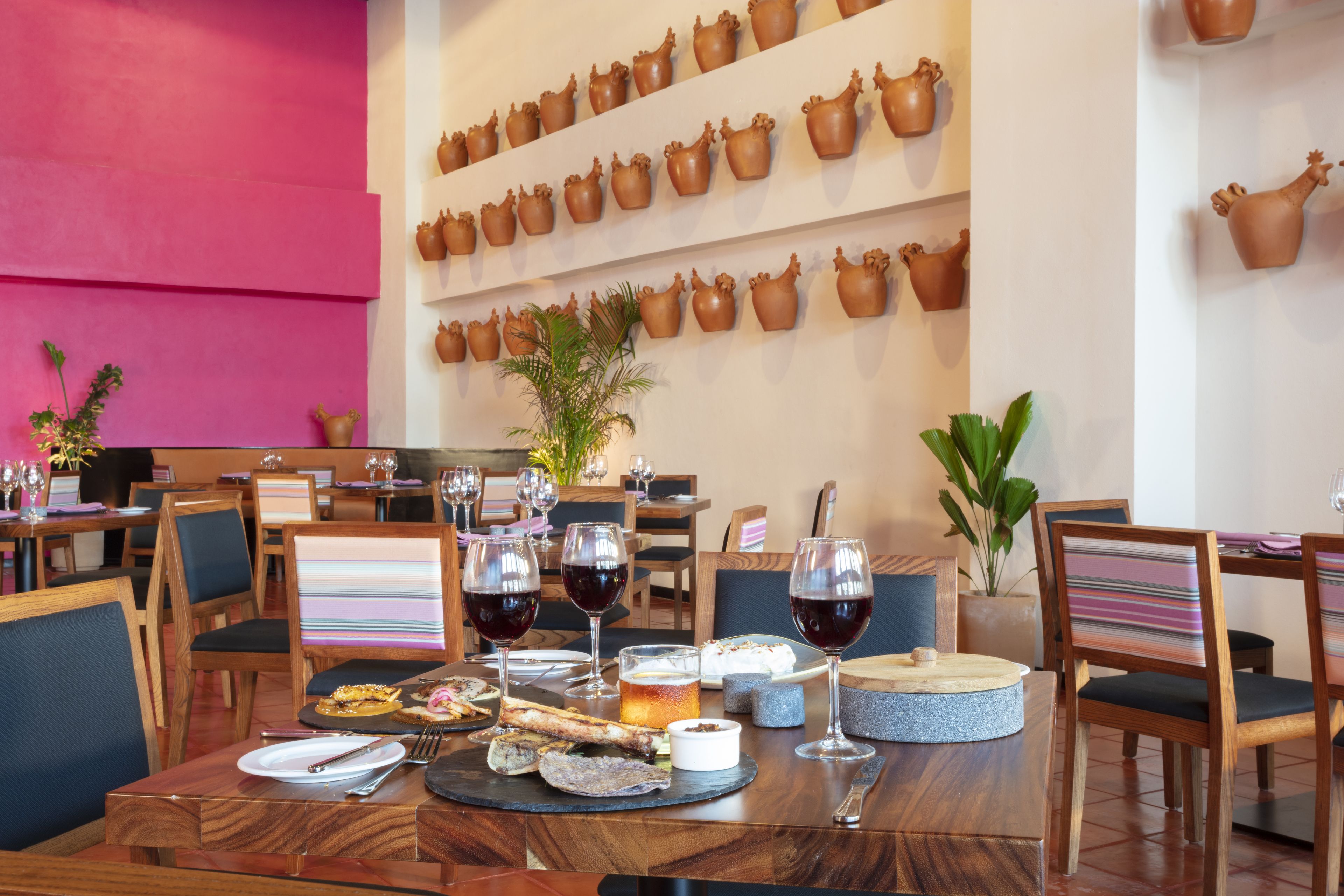 A restaurant interior with wooden tables, chairs, and a wall decorated with pottery.