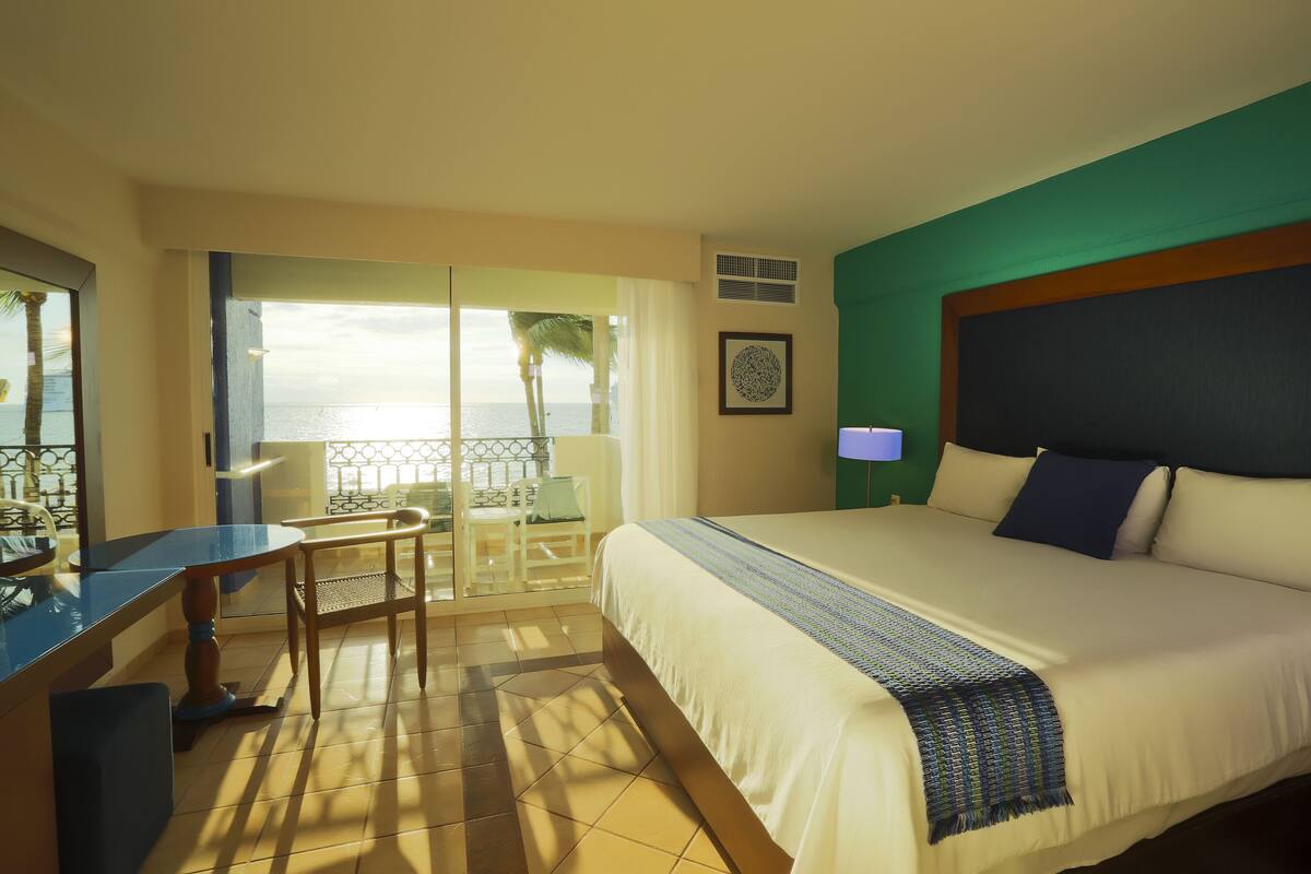 Une chambre d’hôtel avec un lit, un bureau et une vue sur l’océan.