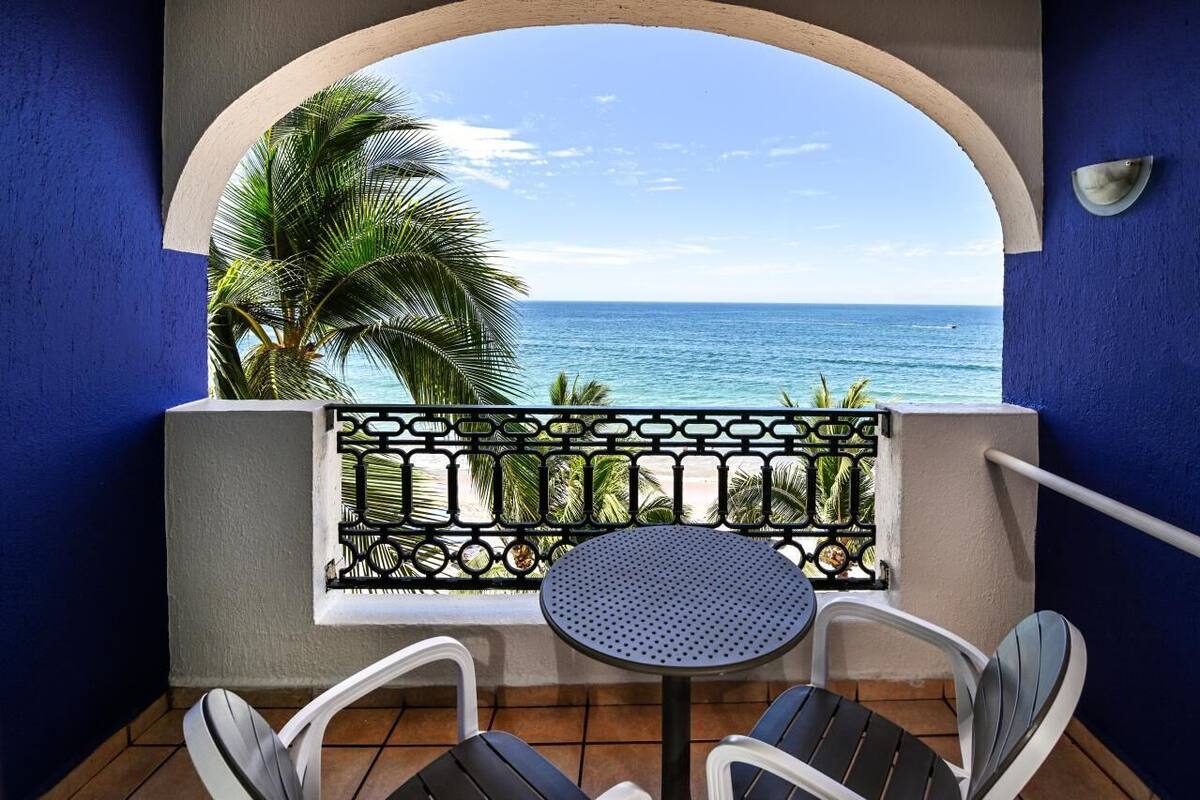 Un balcon avec vue sur l’océan, une table ronde et deux chaises.