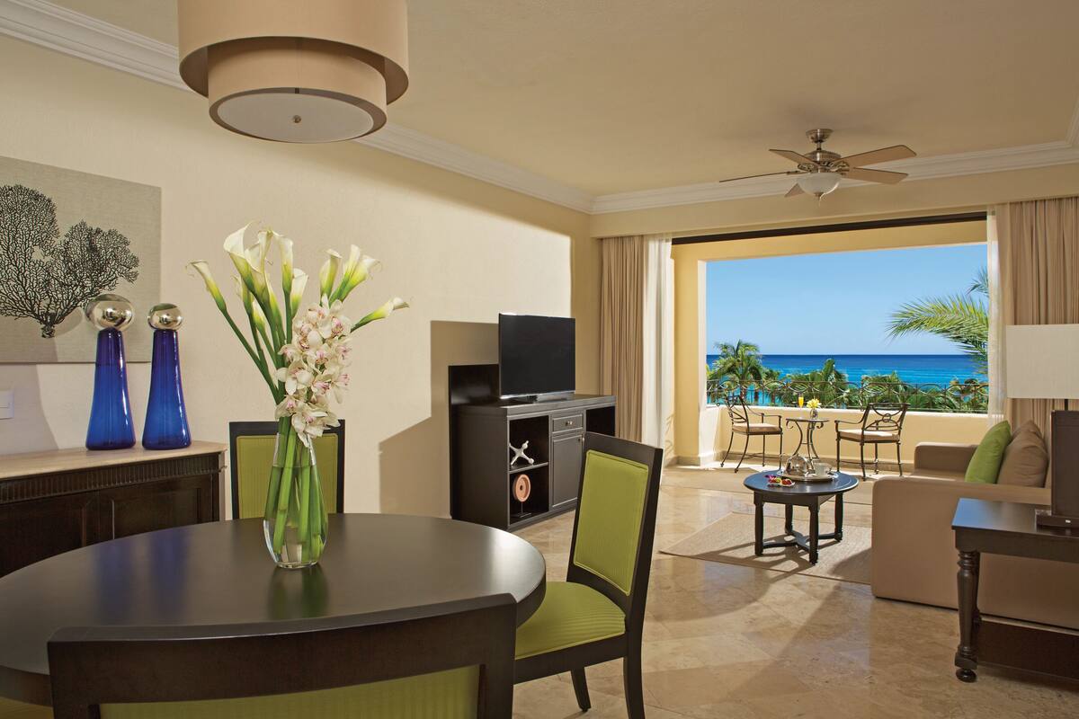 Hotelkamer met een eethoek, televisie en balkon met uitzicht op de oceaan.