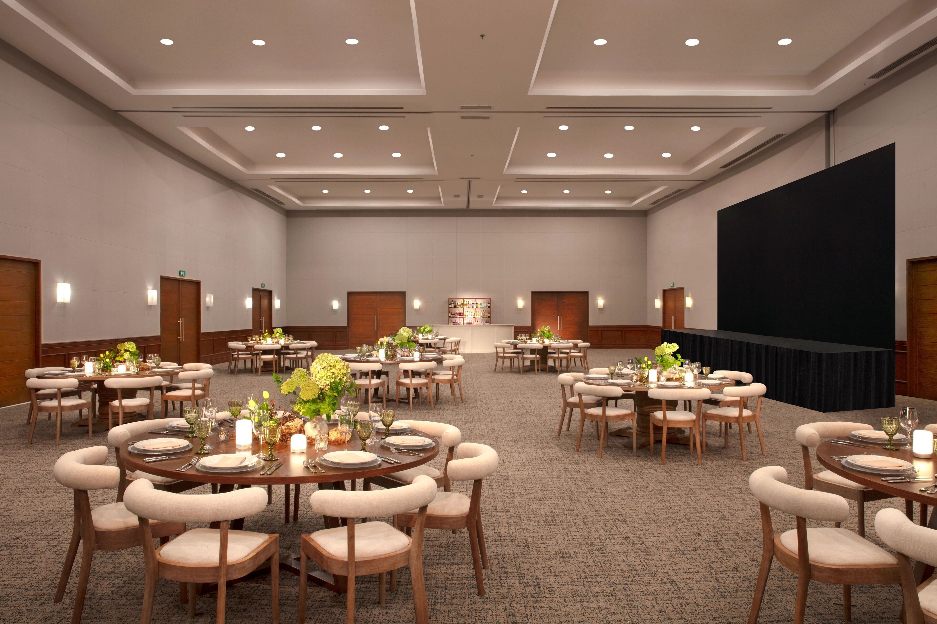 A large conference room with multiple round tables set for dining, equipped with chairs and table settings.