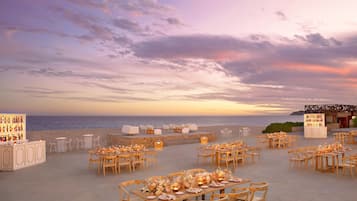 Un área de comedor al aire libre con mesas dispuestas para una comida, con vista al mar.