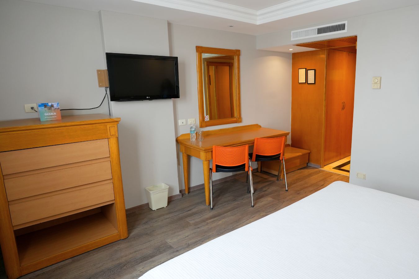 Una habitación de hotel con una cama, un escritorio con dos sillas, un televisor y un armario.