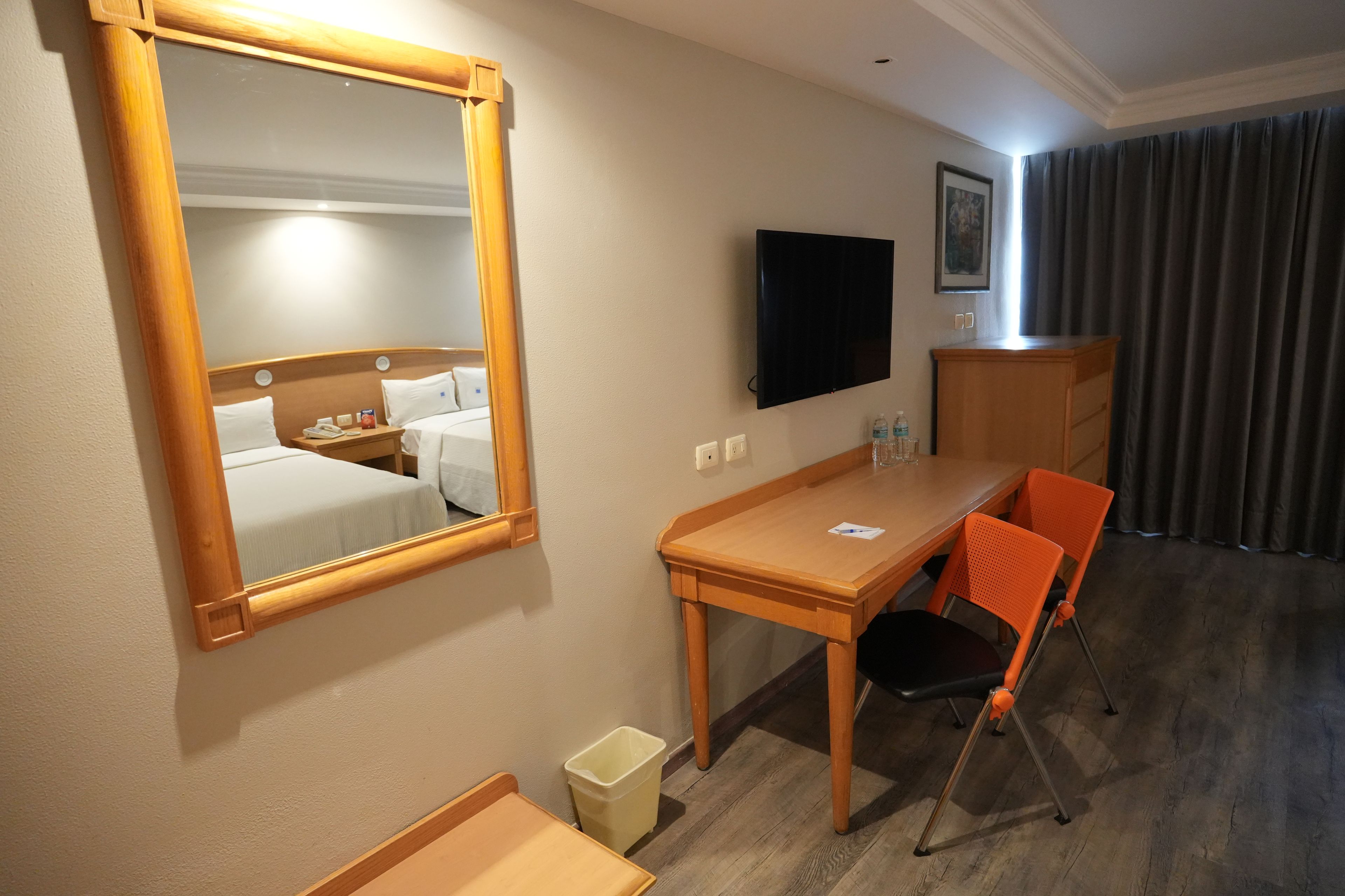 A hotel room with a bed, a desk, a chair, a television, and a window with curtains.