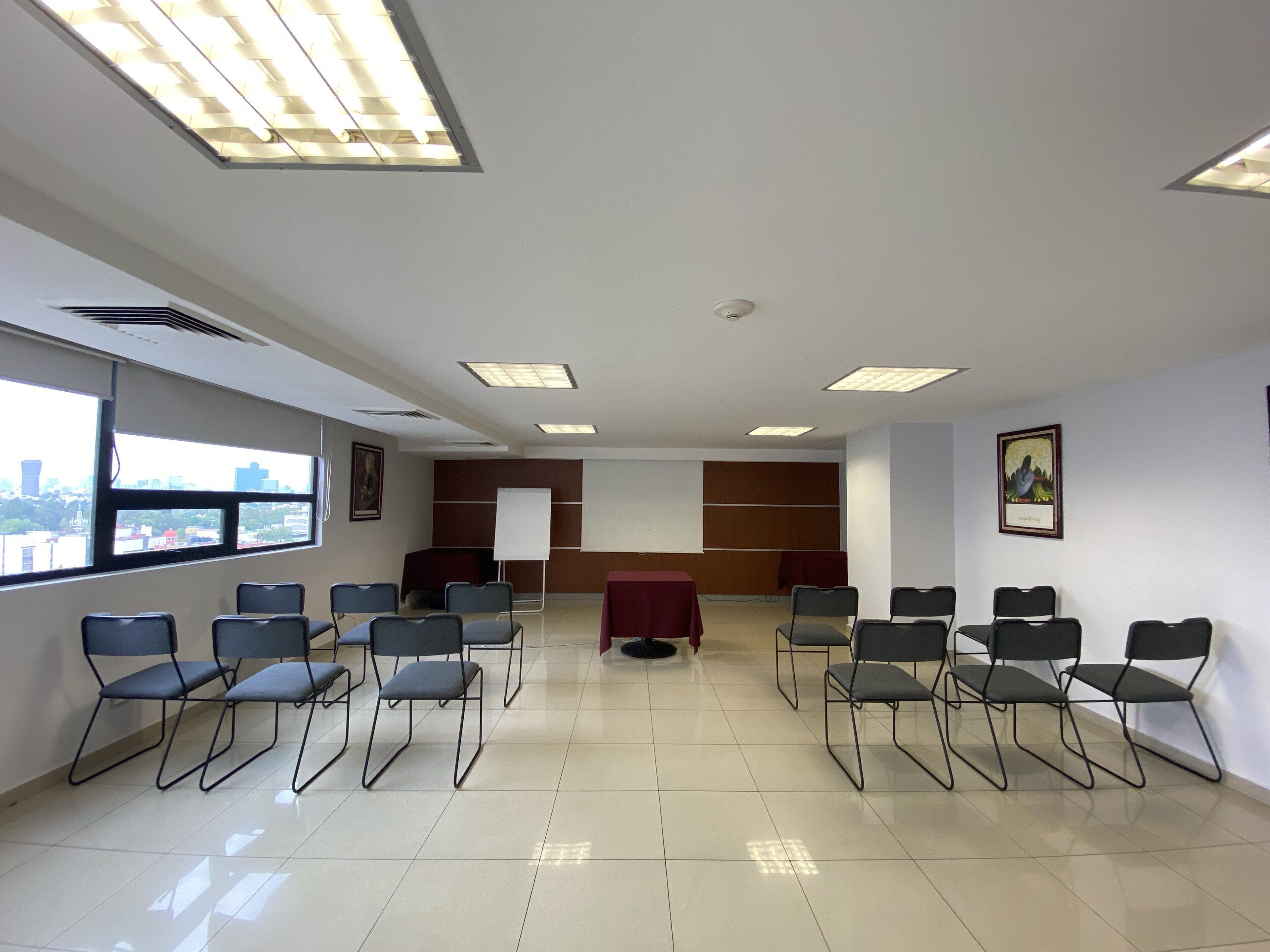 A conference room with a whiteboard, chairs, a table, and a city view through large windows.