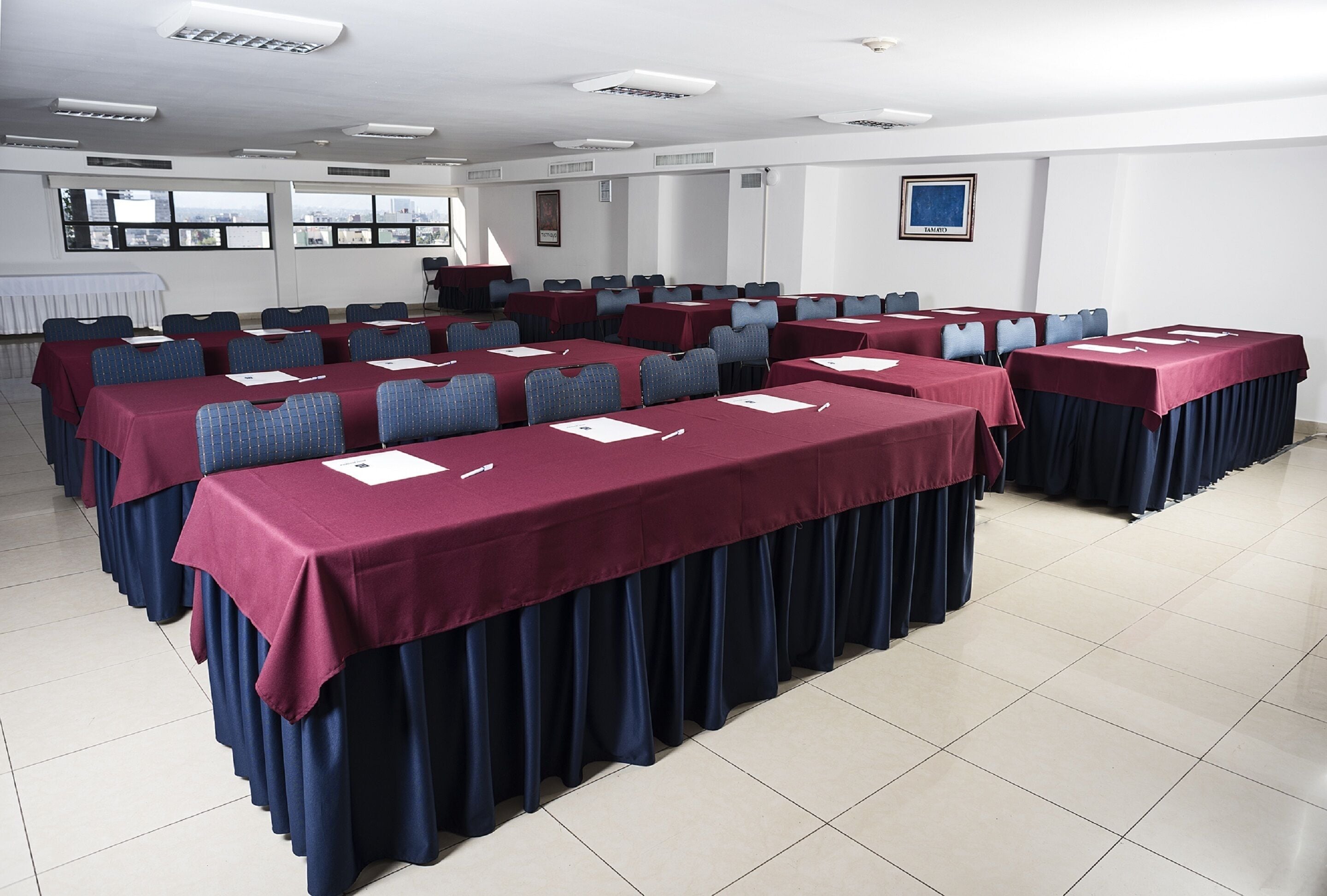 Une salle de conférence équipée de plusieurs tables, de chaises et d’un pupitre.