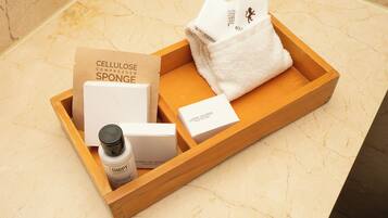 Una bandeja de madera con diversos productos de spa, incluyendo una botella de loción, una esponja y cajas de productos de baño.