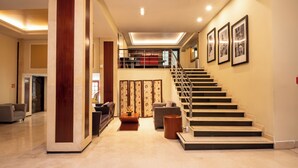Un hall amplio con una escalera moderna, un área de descanso y un panel decorativo en la pared.