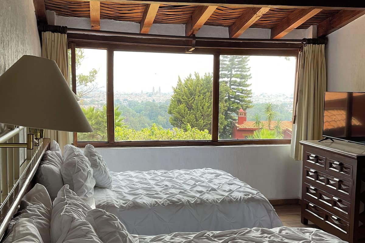 Une chambre avec un grand lit, une commode et une fenêtre donnant sur la ville.