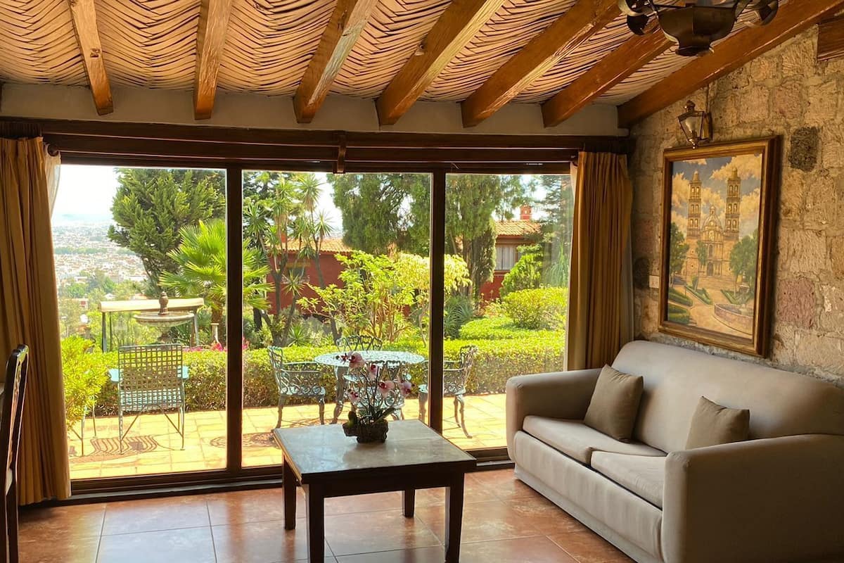 Un vaste espace de vie avec une porte-fenêtre coulissante donnant sur une terrasse, un canapé, une petite table et un tableau accroché au mur.