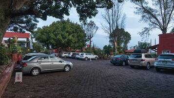 A parking area with multiple cars, trees, and buildings in the background.