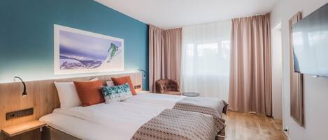 Habitación de hotel con una cama grande, un escritorio, una silla, un televisor y un cuadro en la pared.