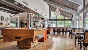 A spacious restaurant with a wooden buffet counter, large windows, and a chandelier. - Nordfjord Hotell (Stad)