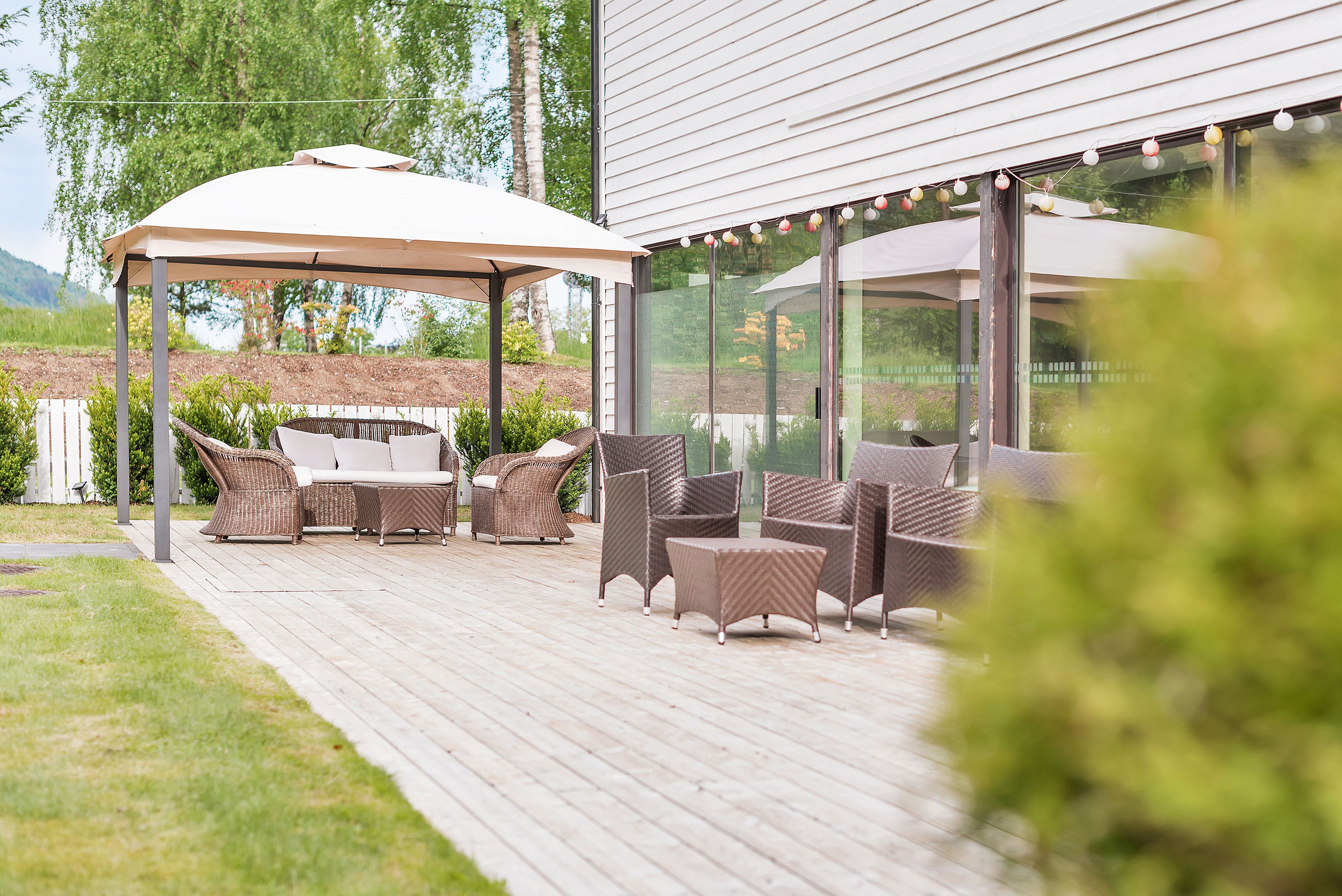 Un patio al aire libre con mobiliario de mimbre, una zona de estar cubierta y vistas del paisaje circundante.