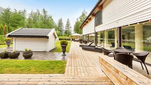 A wooden deck with outdoor furniture, a small shed, and a house with large windows. - Nordfjord Hotell (Stad)