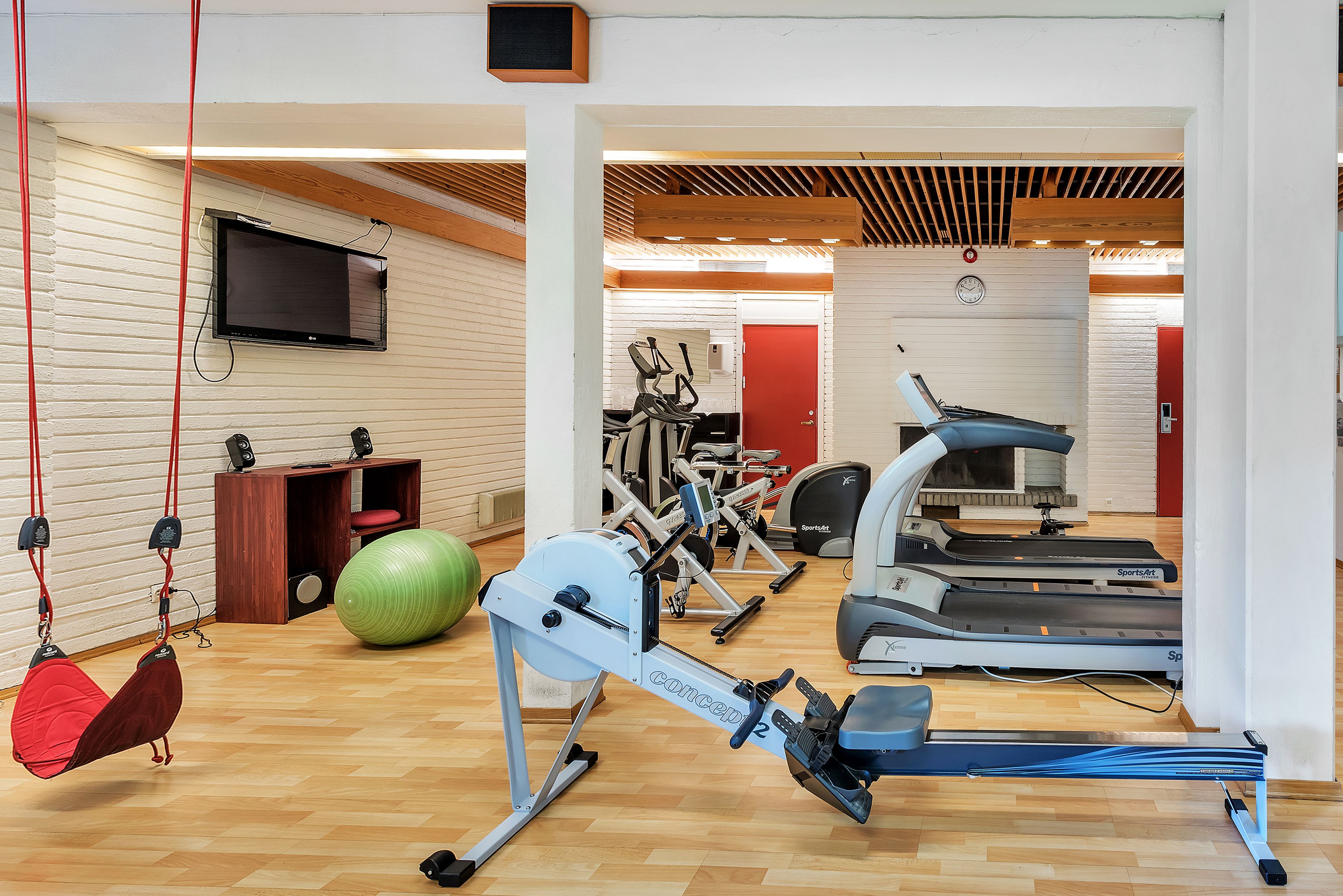 Una palestra con attrezzature per allenamento, tra cui un vogatore, tapis roulant e una cyclette.
