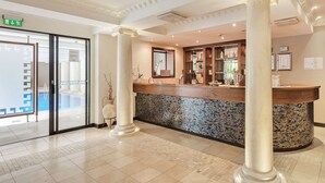A reception area with a marble counter, columns, and a tiled floor. - Nordfjord Hotell (Stad)